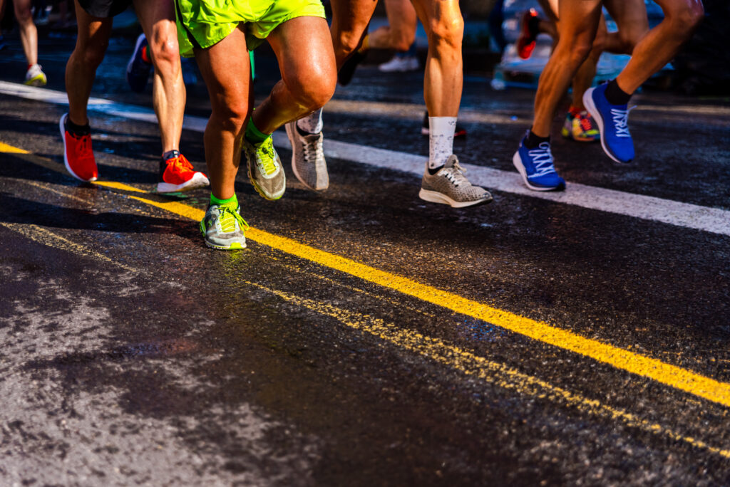 Muscled legs of a group of several runners training running on asphalt